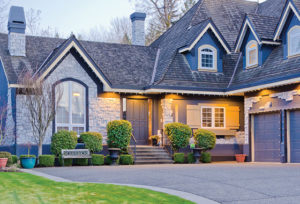 Beautiful blue house exterior with stonework and bushes at dusk